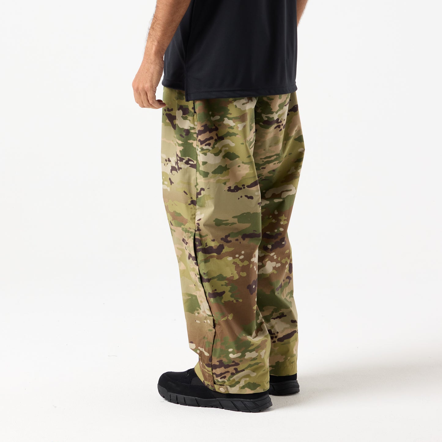 A person wears DFND Assault Pants with a black shirt and black shoes, standing against a plain white background.