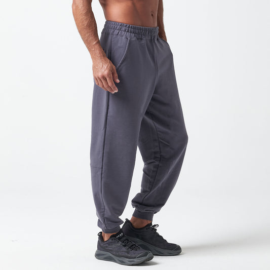 A person wearing charcoal gray joggers and black sneakers stands against a light background.