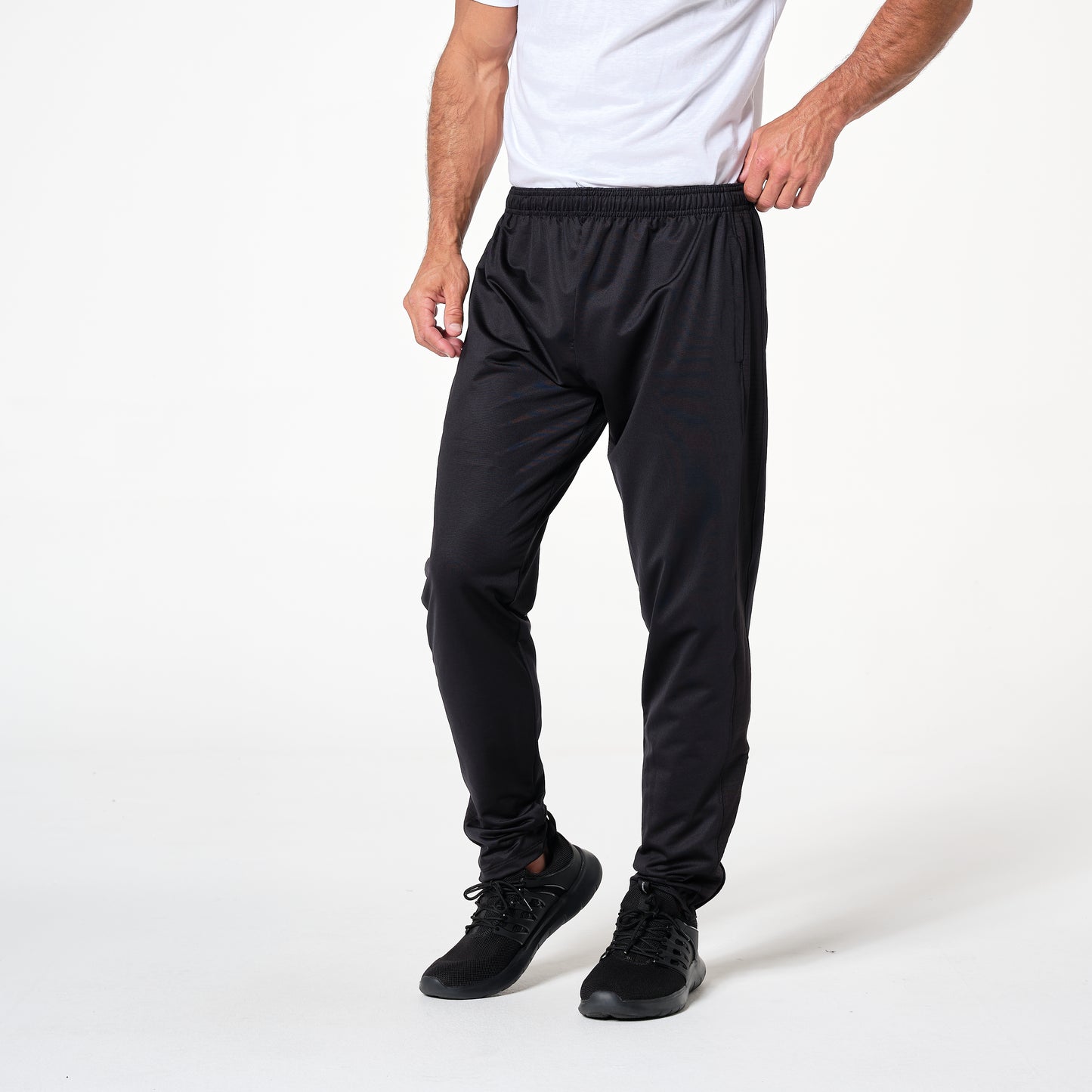 A person in a white shirt and black athletic pants stands in a neutral pose on a plain background.