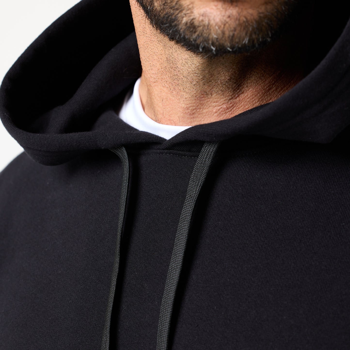 Close-up of a person wearing the DFND TITAN FLEECE HOOD over a white T-shirt, showing only the lower face and upper chest—gear designed for cold weather training.