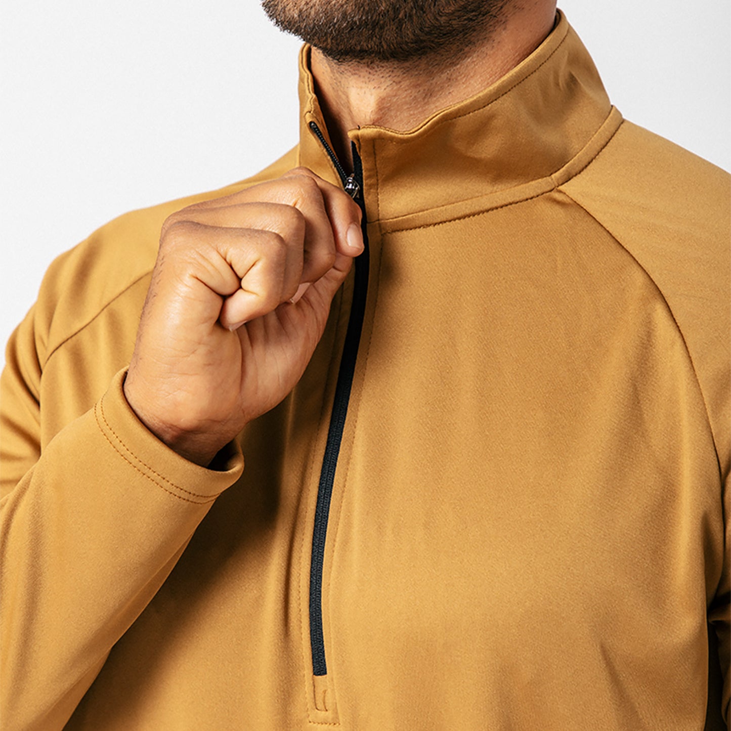 Person in a tan zip-up jacket adjusting the zipper. Upper body view, with a plain white background.