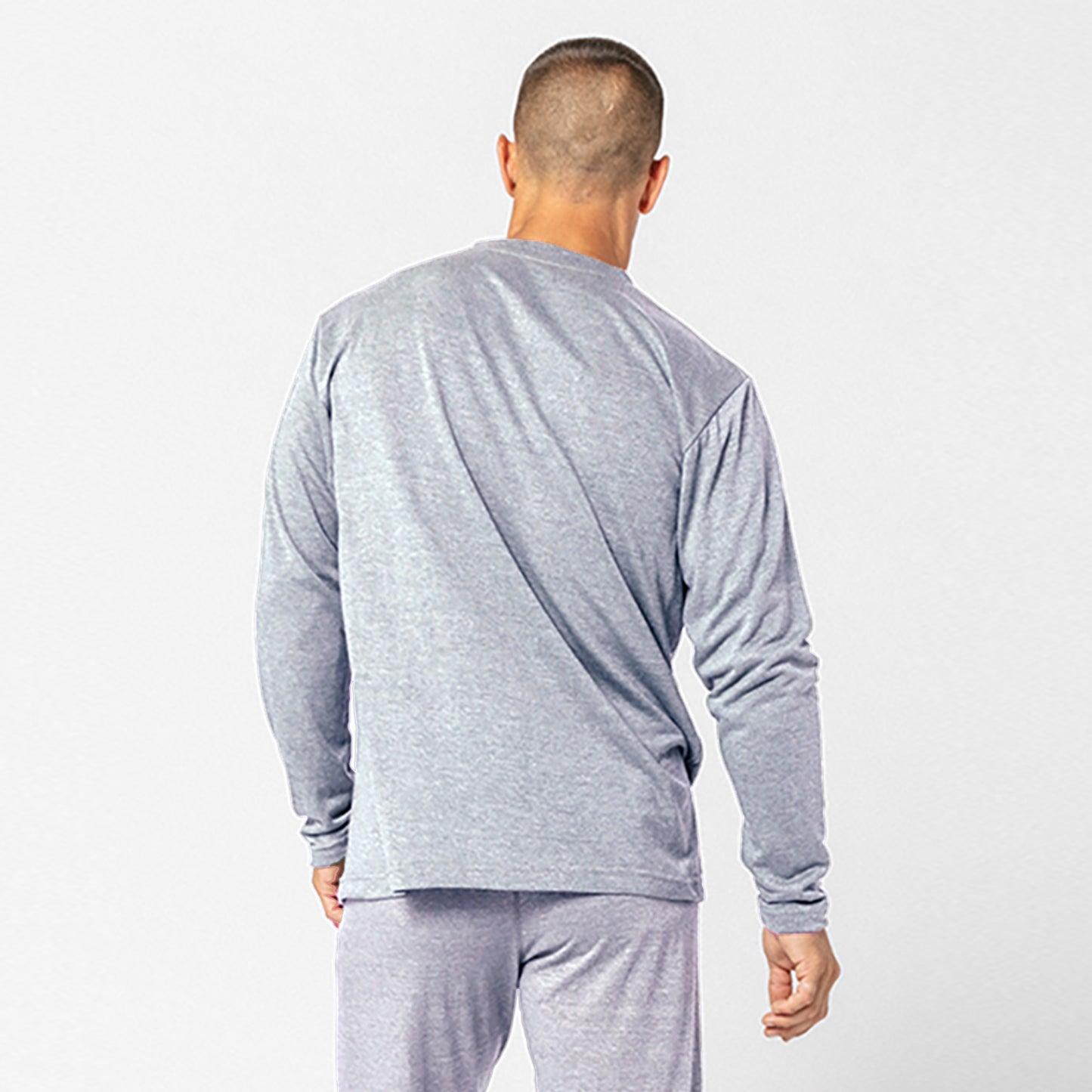A man wearing the DFND Cooling Recovery Sleepwear LS Shirt, a gray long-sleeve top made with CELLIANT minerals, is shown from the back against a plain background—this DFND sleepwear is designed to enhance sleep quality.