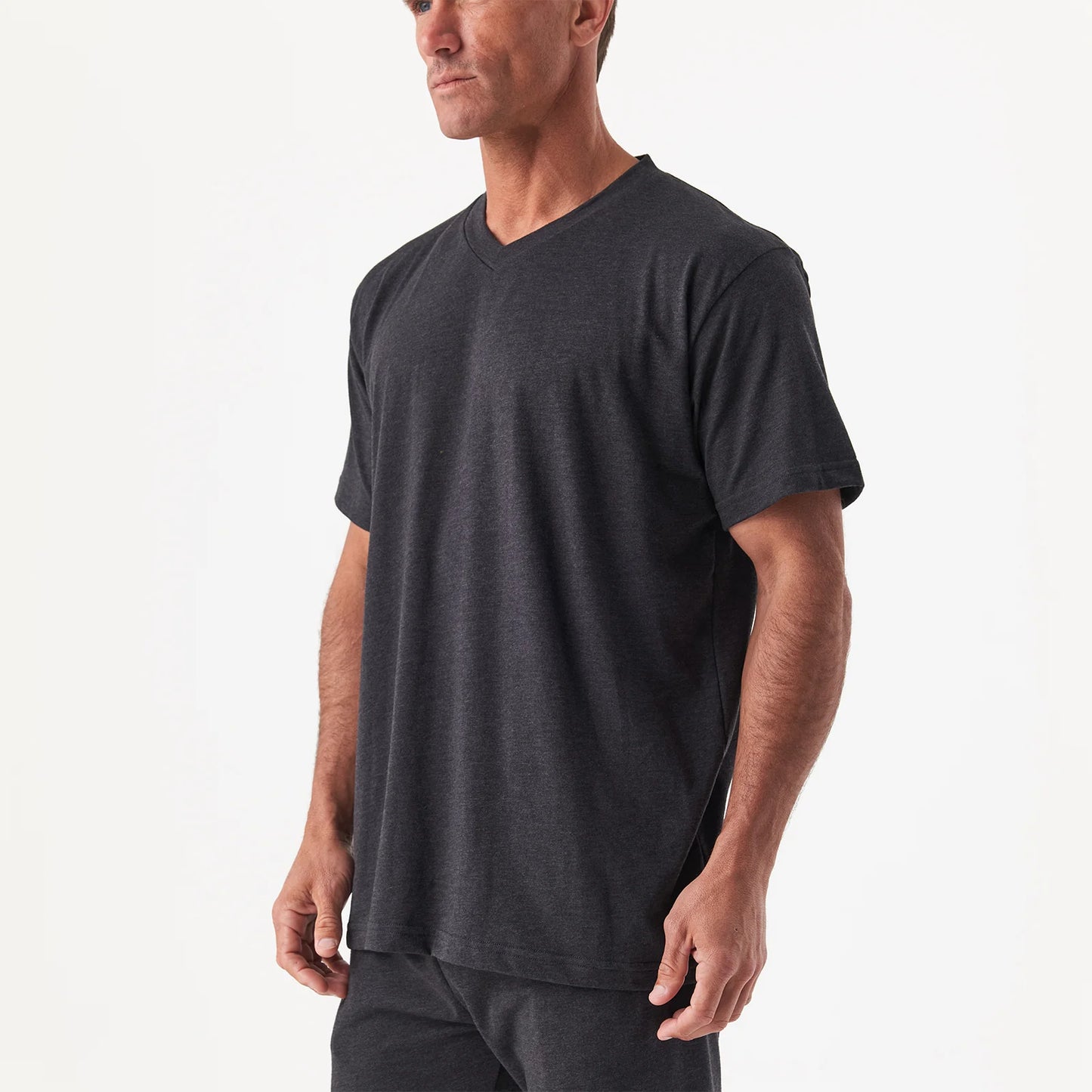 A man wears the DFND Sleepwear SS Shirt & Shorts in dark gray, featuring CELLIANT technology for recovery sleepwear, standing against a plain white background.