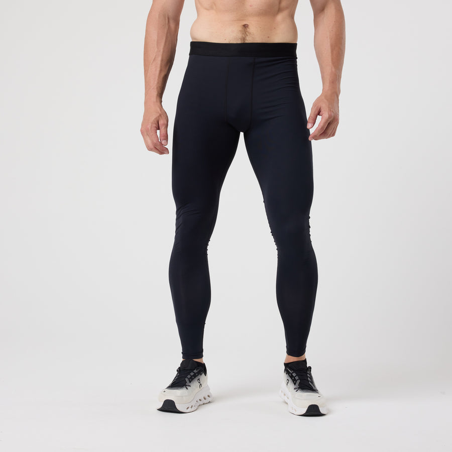 A person wears DFND ACTIVE Ax COMPRESSION TIGHT leggings with graduated compression and white sneakers, standing against a plain white background.