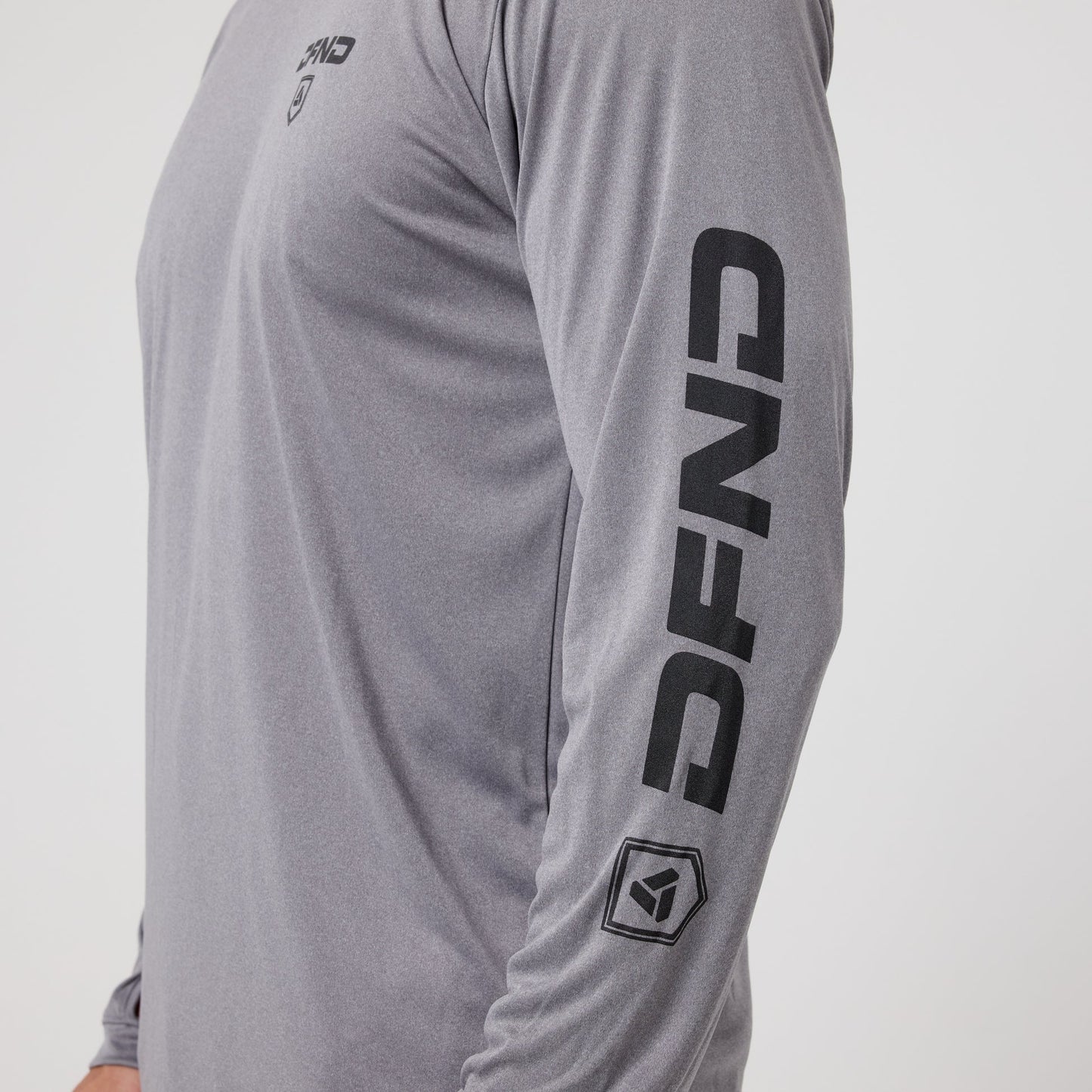 A person in the DFND Speed Tech Hoodie + Aero Short Outdoor Kit, featuring a long-sleeve gray athletic hoodie with "DFND" printed boldly on the chest and sleeve.
