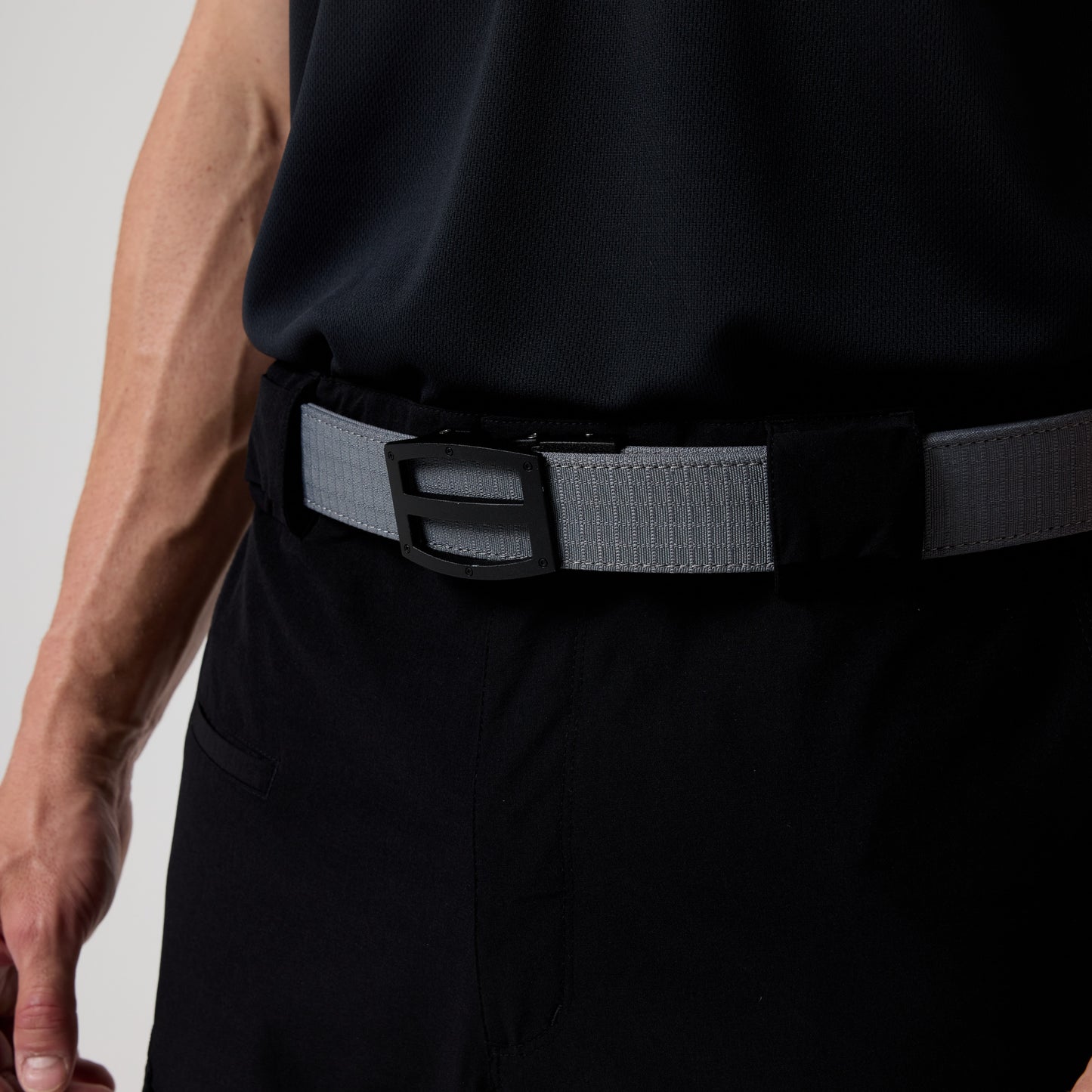 A close-up of a person wearing the DFND GALAXY PERFORMANCE POLO, paired with black pants and a gray belt with a rectangular black buckle.