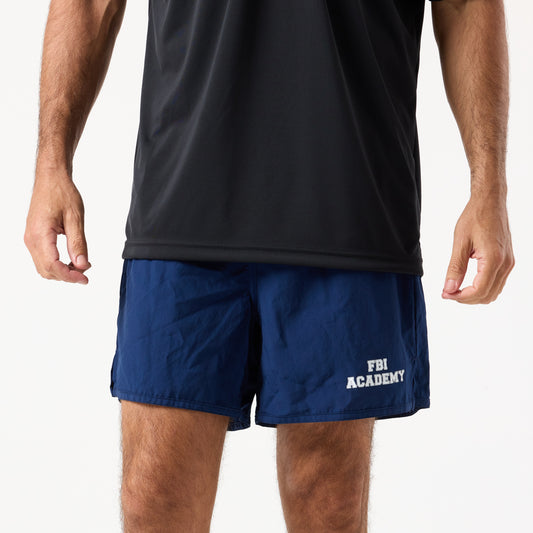A person wears DFND MALIBU 5" PT SHORTS FBI ACADEMY—blue, Berry Compliant, made in the USA—with "FBI Academy" on the left leg. Face not visible. Black shirt also worn.