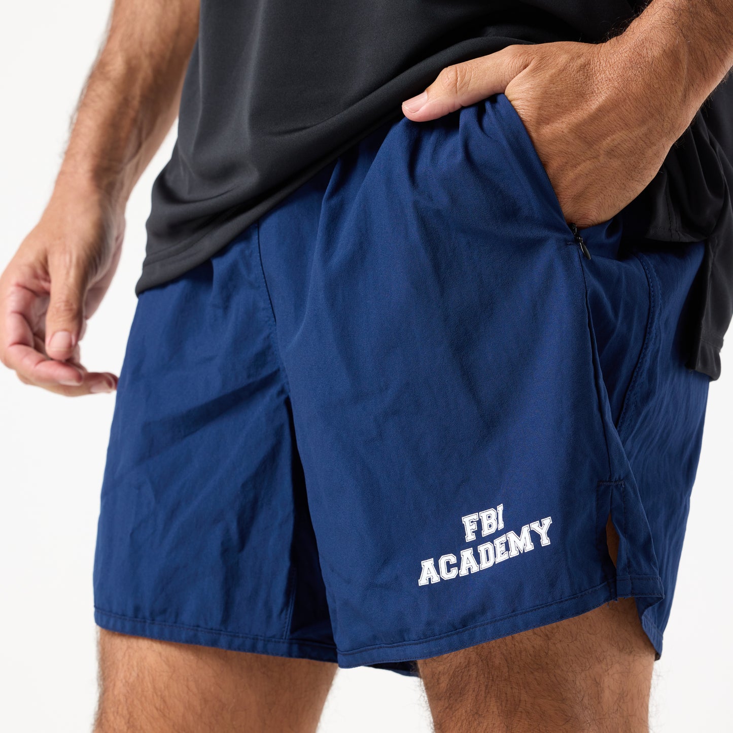 A person is wearing DFND MALIBU 5" PT SHORTS FBI ACADEMY, which are blue with "FBI ACADEMY" in white on the left leg and Berry Compliant, made in the USA.