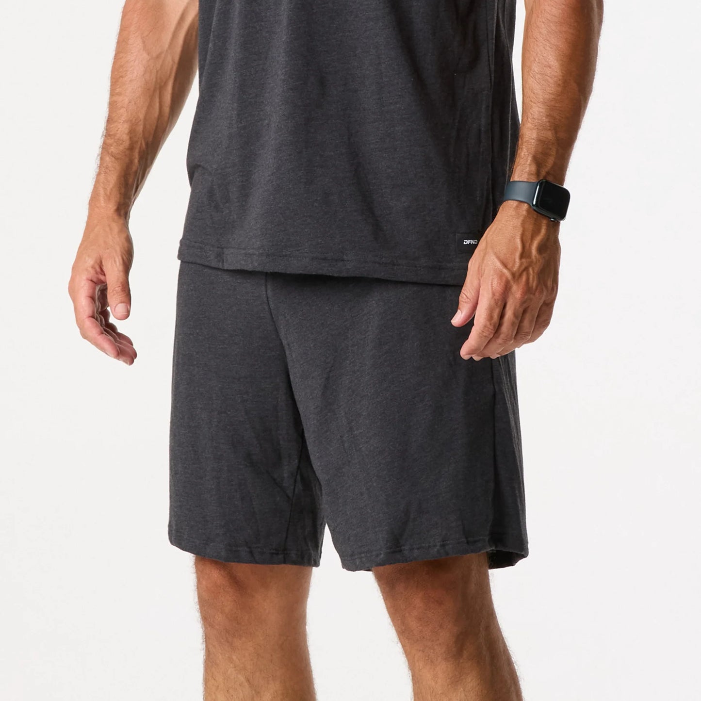 A person wearing a black smartwatch and DFND Sleepwear SS Shirt & Shorts in dark grey stands against a plain white background.