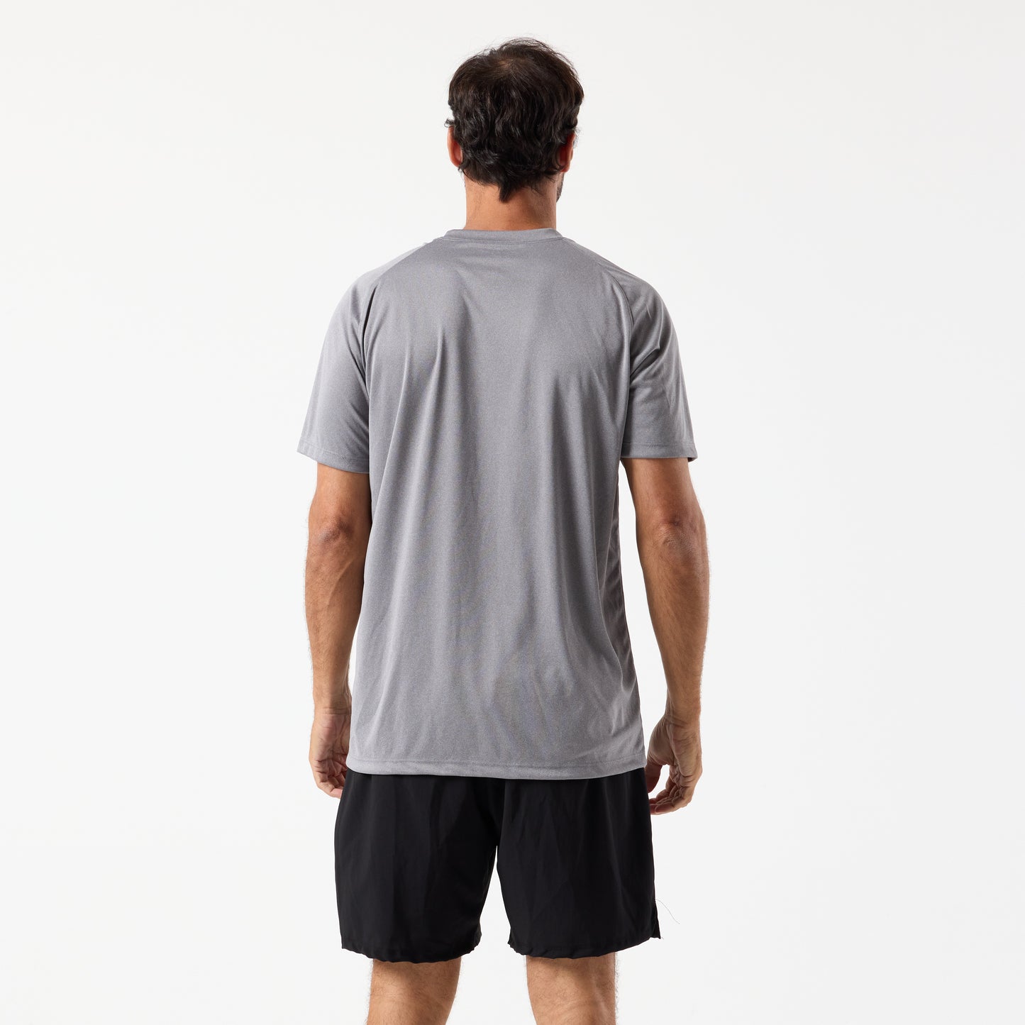 A man faces away from the camera, wearing a gray DFND SPEED TECH SS SHIRT - Raglan Sleeve with moisture-wicking tech and black shorts, set against a plain white background.