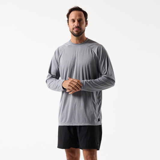 A man stands against a plain white background wearing the DFND SPEED TECH LS SHIRT with raglan sleeves and black shorts.