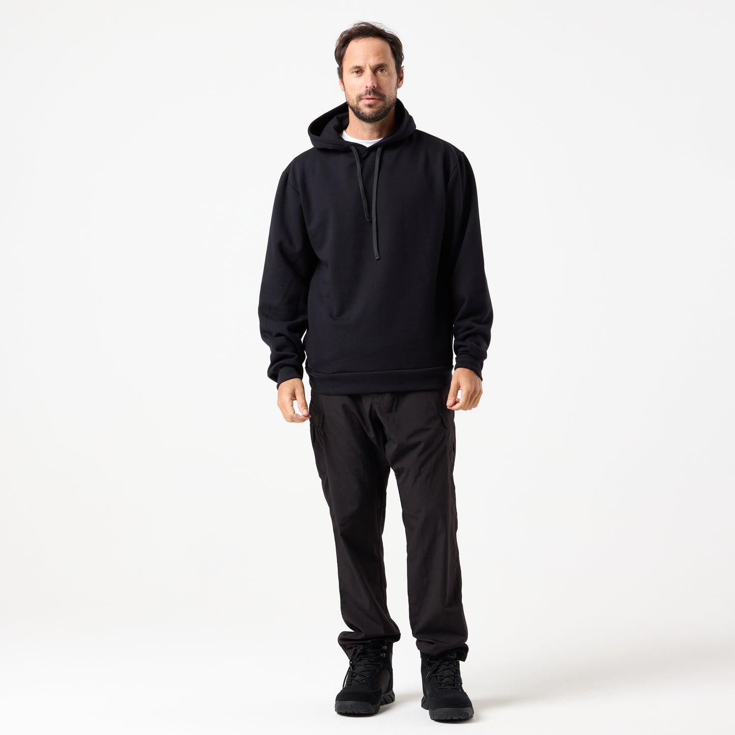 A man faces forward against a white background, wearing the DFND TITAN FLEECE HOOD, black pants, and black shoes—perfect for cold weather training.