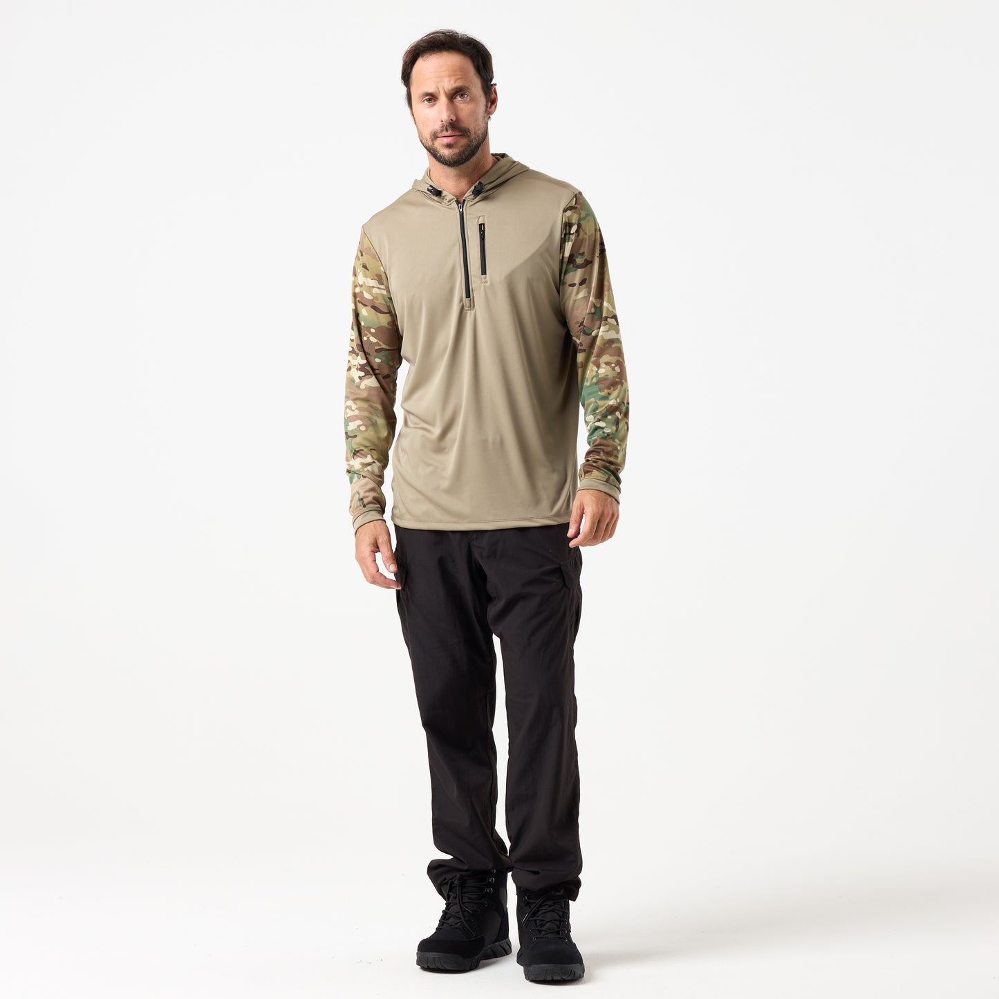 A man wears the DFND SPEED TECH HOODED 1/4 ZIP, a tan hoodie with camouflage antimicrobial sleeves, styled with black pants and boots, standing against a plain white background.