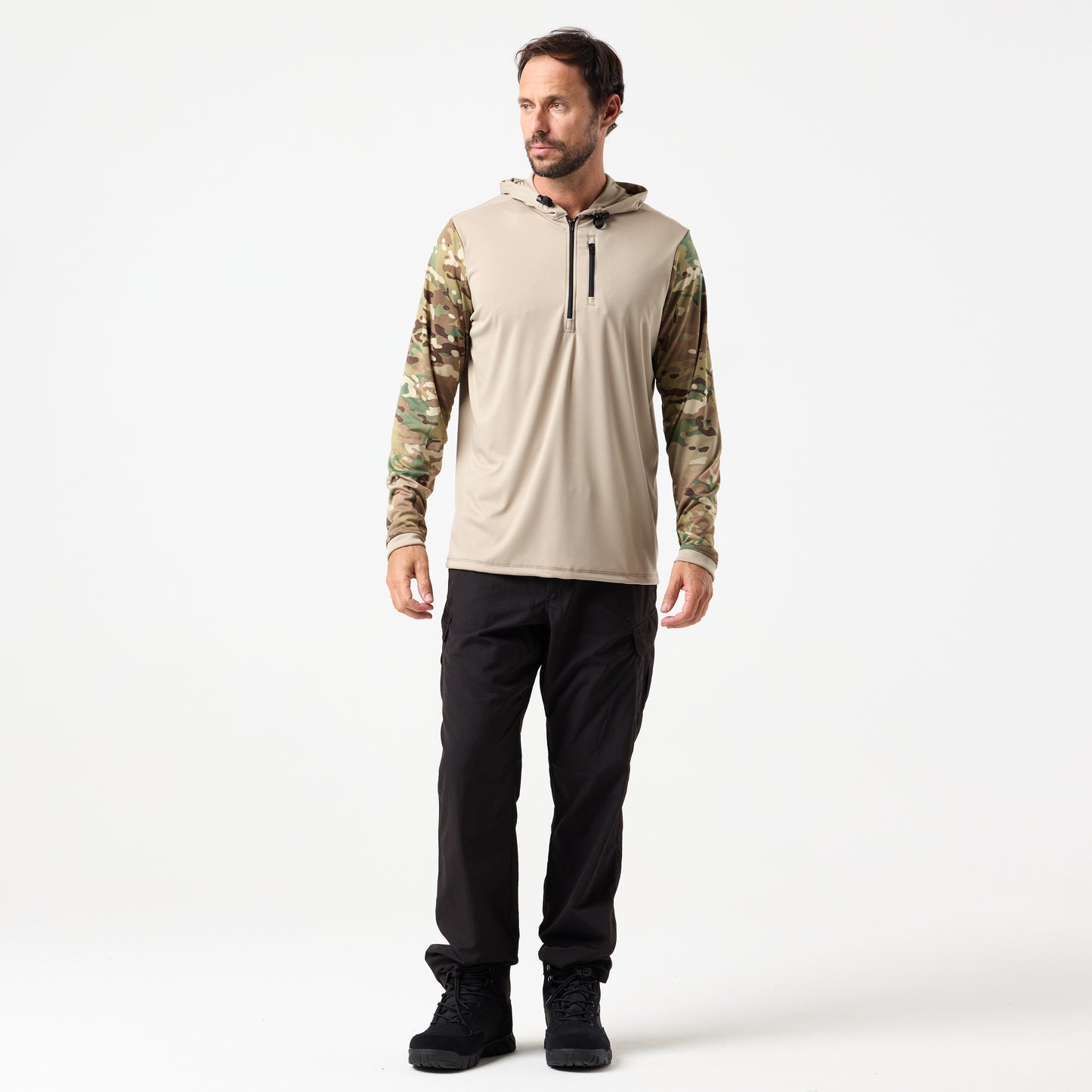 A man faces left against a white background, wearing the DFND SPEED TECH HOODED 1/4 ZIP—a tan lightweight performance shirt with camouflage sleeves—and black pants.