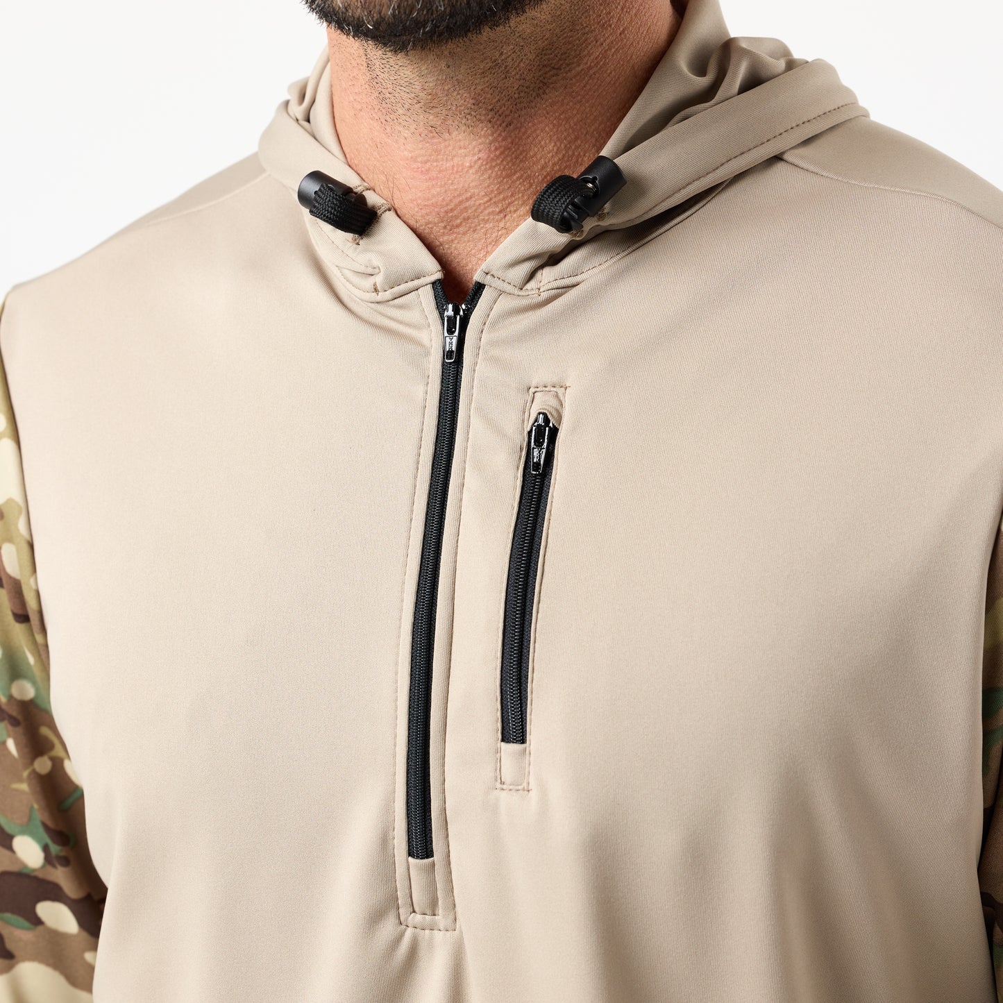 A close-up of a person wearing the DFND SPEED TECH HOODED 1/4 ZIP, featuring a chest zipper pocket, camouflage-patterned sleeves, and performance fabric for comfort.