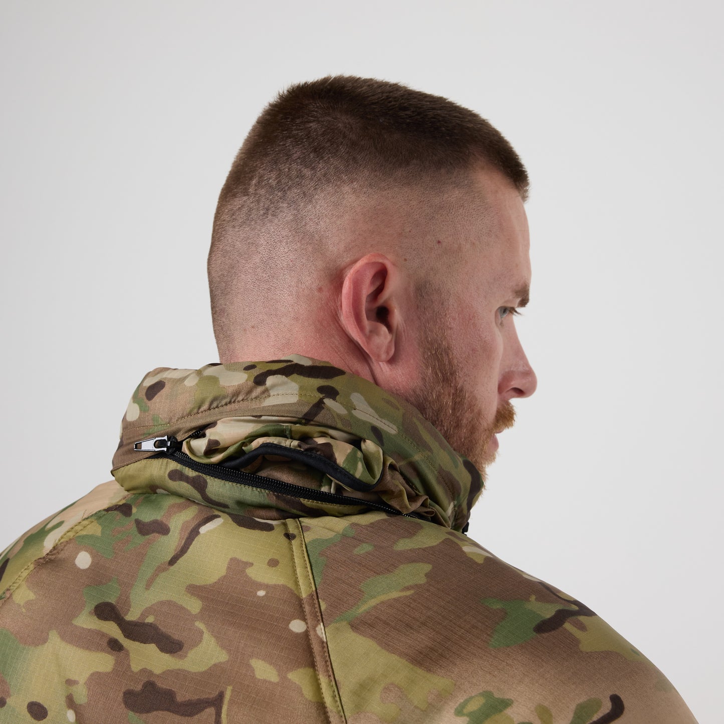 Man with short hair and beard wearing a DFND Warrior Insulated Jacket with a DWR shell, shown from the back and turned slightly to the side against a plain background.