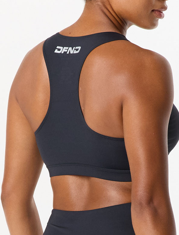 Person wearing a black sports bra with "DFND" logo on the back, facing away from the camera.