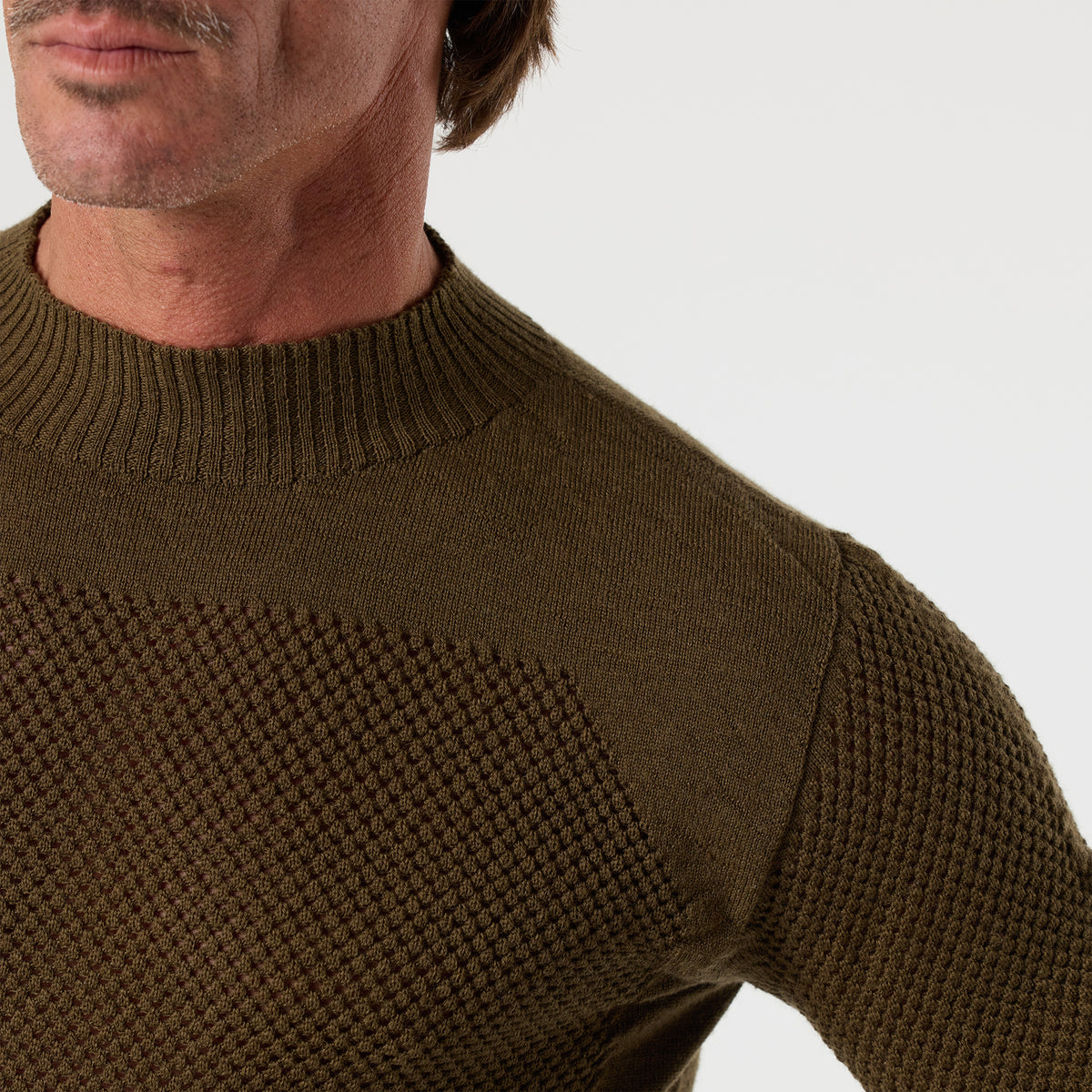 A man with a mustache is pictured from the shoulders up against a plain background, wearing the DFND TAHOE WOOL MESH LONG SLEEVE SHIRT in olive green.