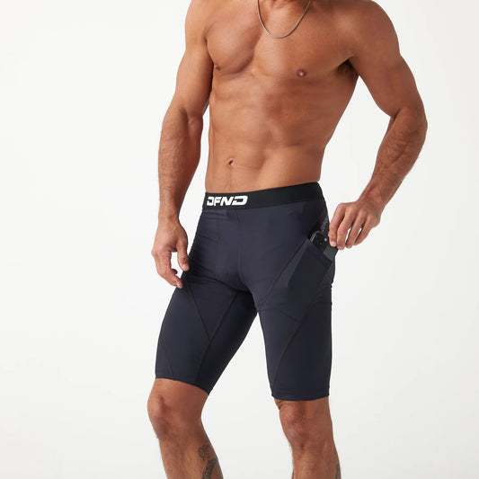 A shirtless person wearing the DFND Compression Short + Shirt Gym Kit with a side pocket pulls an item from the pocket.