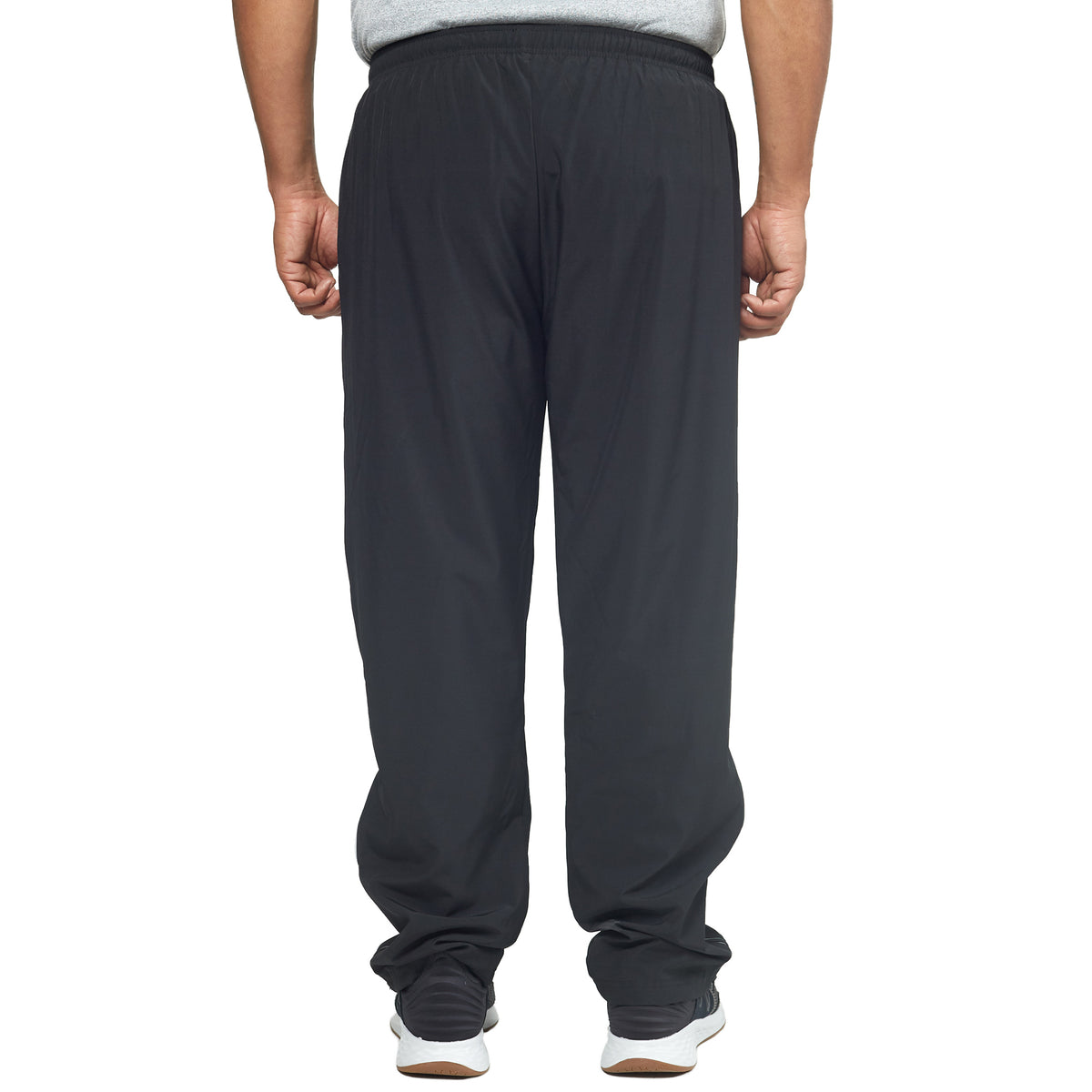 A person wearing DFND’s FLASH TECH PANTS in black—crafted with 4-Way Stretch and Quick Dry fabric—a gray shirt, and black-and-white sneakers is standing with their back facing the camera.