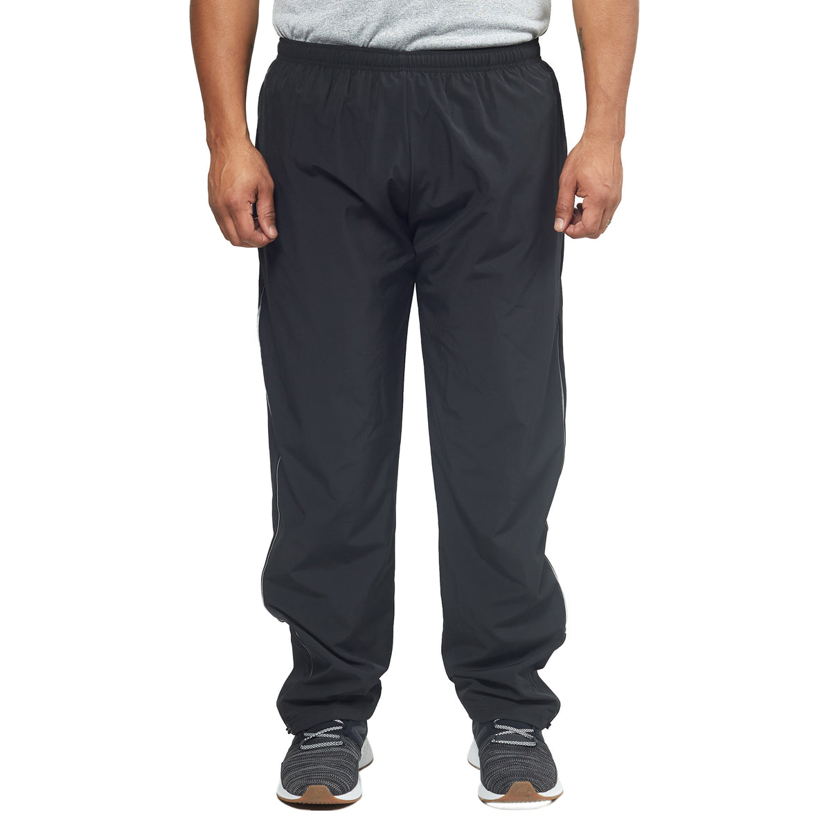 A person wearing a gray t-shirt made with Quick Dry fabric, DFND FLASH TECH PANTS in black, and black sneakers is standing against a plain white background.